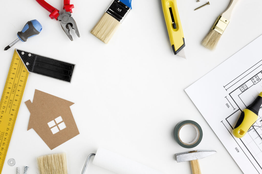DIY tools and house blueprint on a white table, representing home renovation and improvement planning