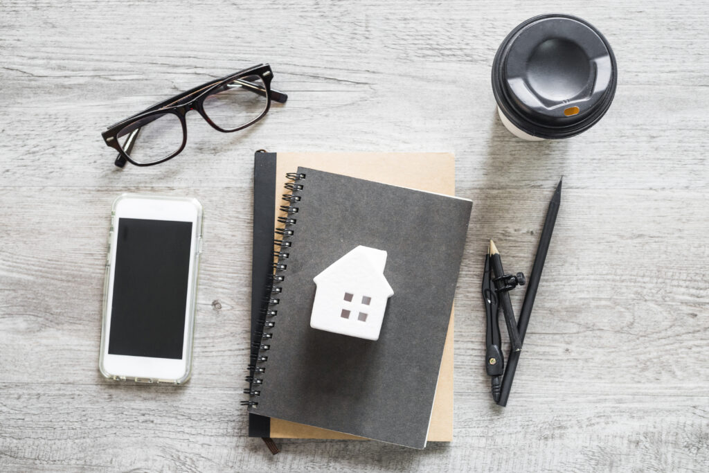 Notebook with house sketch, coffee, glasses, and pen representing home buying planning in Croydon.