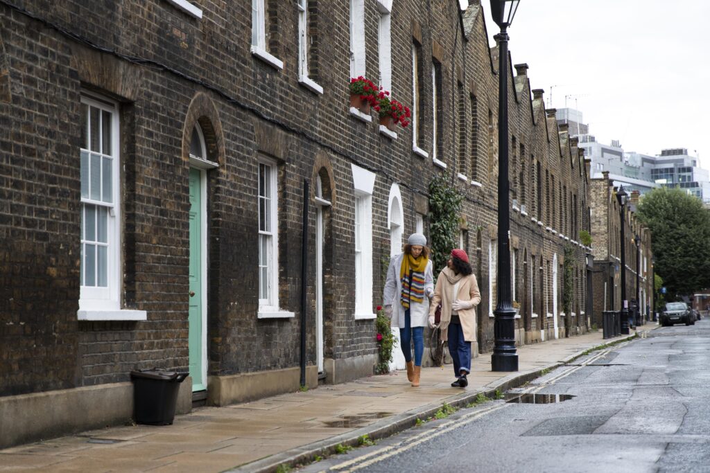Two women walking along a residential street lined with brick houses in Aylesbury, showcasing an affordable and typical Buckinghamshire neighbourhood.