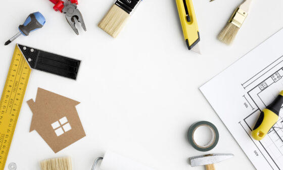 DIY tools and house blueprint on a white table, representing home renovation and improvement planning
