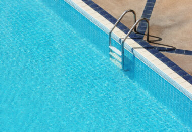 Clean and well-maintained backyard swimming pool with clear blue water and surrounding patio.