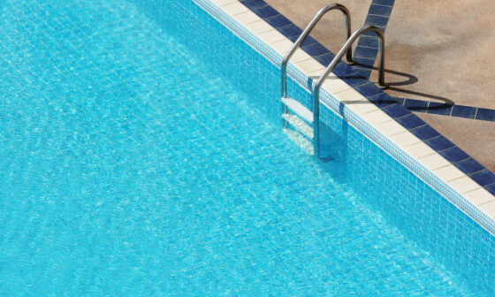 Clean and well-maintained backyard swimming pool with clear blue water and surrounding patio.