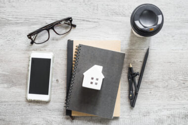 Notebook with house sketch, coffee, glasses, and pen representing home buying planning in Croydon.