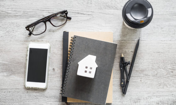 Notebook with house sketch, coffee, glasses, and pen representing home buying planning in Croydon.