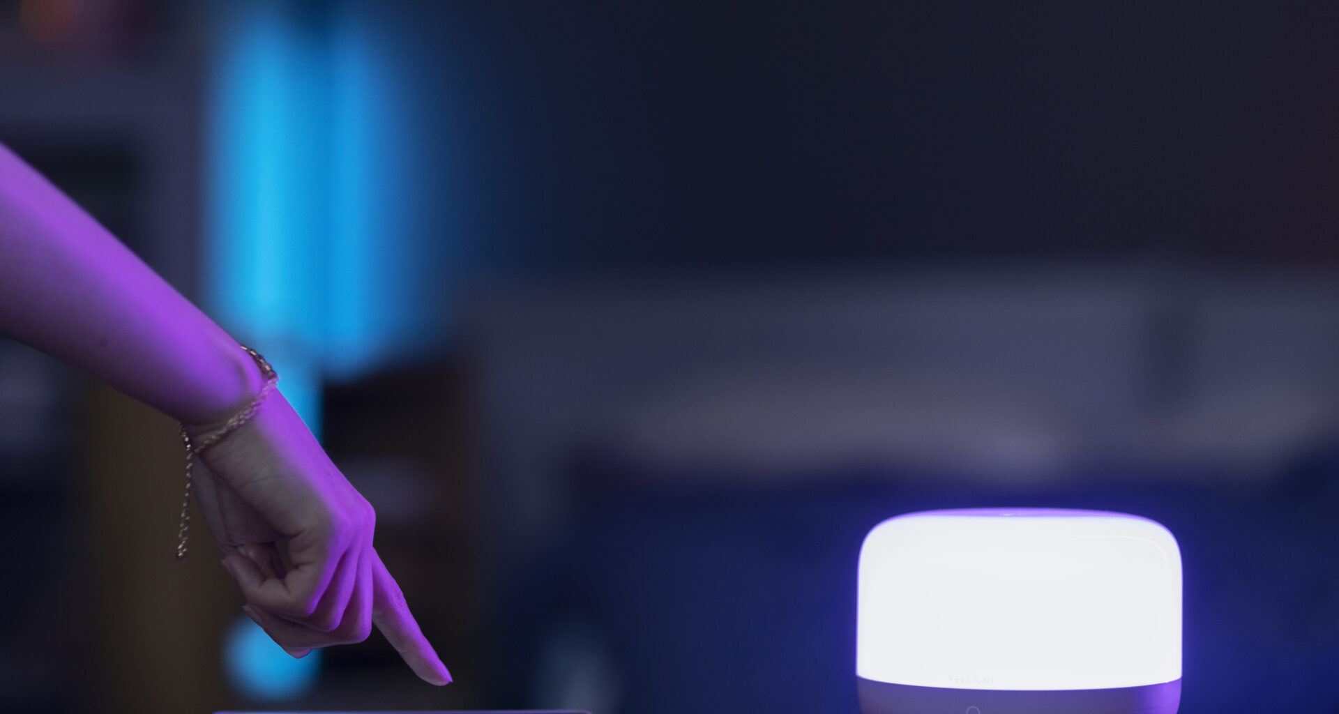 Person controlling smart home lighting with smartphone app in modern living room, ambient light setup